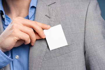 Close up of young corporate male hand showing blank debit card in grey suit. Copy space