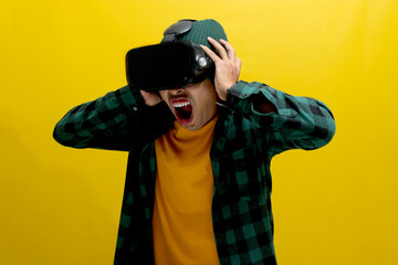 Terrified Asian man wearing a VR headset screams in fear while experiencing a horror movie in VR....