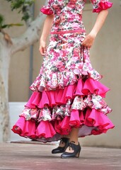A woman in a flamenco dress with ruffles is dancing Sevillanas, a Spanish folk dance