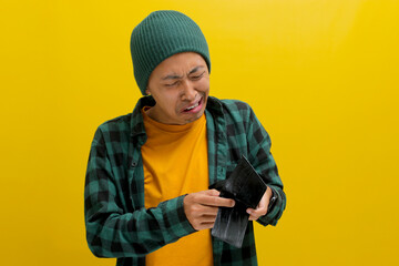 Unemployed Asian man appears bewildered and speechless as he gazes at his empty wallet, facing...