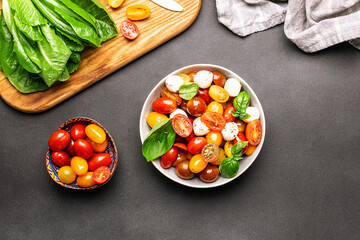 Fresh juicy homemade caprese salad with baby mozzarella cheese, cherry tomatoes, basil leaves and...