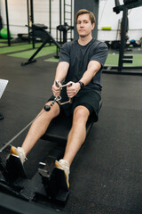 Vertical portrait of beginner sportsman doing exercises on fitness machine in gym. Motivated sporty male with pull cable or equipment for health goals at sport club. Concept of healthy sports life.