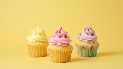 Delicious sweet colorful birthday cupcakes decorated with butter cream on yellow background