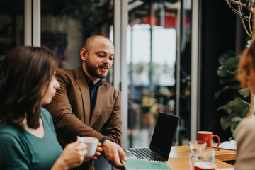 Professional colleagues in smart casual wear engage in a business discussion over coffee with a...