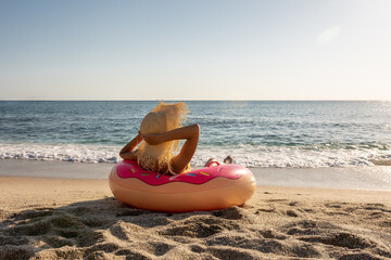 Happy woman with inflatable donut on a tropical beach. Summer vacation concept.