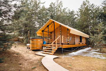 A glamping house with a swimming hot tub in a pine forest. 