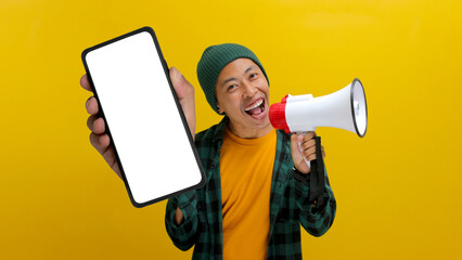 Excited Asian man shows a phone with an empty blank screen for copy space while holding a megaphone...