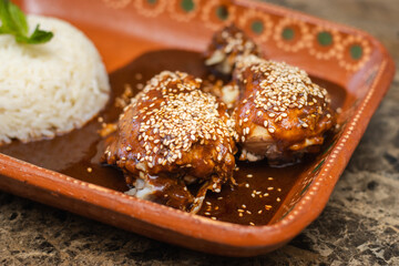 close-up of chicken pieces dipped in mole sauce next to white rice, Mexican food