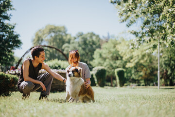 Joyful young adults playing with a fluffy dog in a green park on a sunny day, embodying friendship...