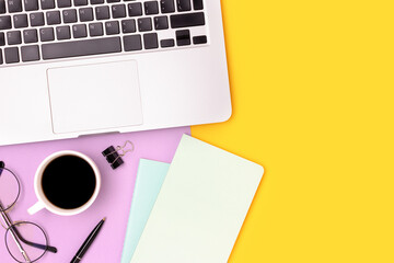 Workspace with laptop, cup of coffee and stationery on a purple and yellow background. Online...