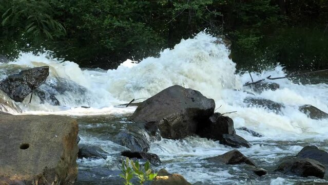 Strong river crashing against a rock.  Horizontal slow motion video