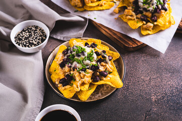 Mexican baked nachos with chicken, black beans and cheese on a plate on the table