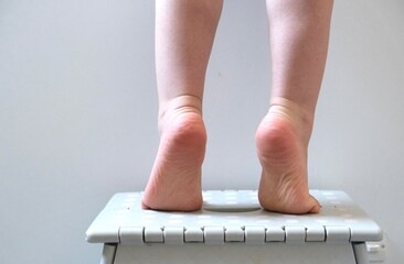 Baby feet. The baby stood on tiptoe. Baby feet on white background. A child washing dishes.