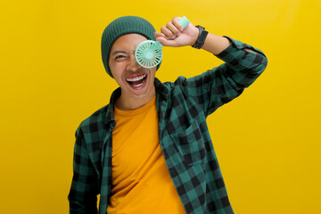 A young Asian man, dressed in a beanie hat and casual shirt, holds a handheld portable electric...