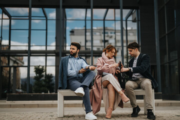 A group of business colleagues brainstorming together while sitting outside an office building, exuding teamwork and a collaborative spirit.