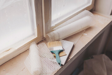 a paint brush on a windowsill ready to fix the wall. Apartment under construction in the new...