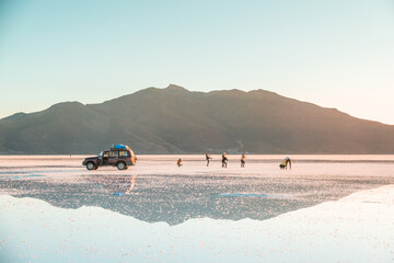 Reflections at Salar de Uyuni during sunset -April- - 4x4 Jeep and tourists behind mountain and mirror lake