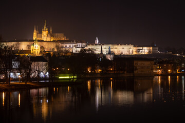 Obraz premium Illuminated Hradcany (Prague Castle) and Charles Bridge, St. Vitus Cathedral and St. George church, medieval architecture, Vltava river at night, Bohemia, Czech Republic.