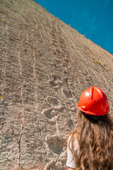 Girl looking at Cal Orcko near Sucre in Bolivia: wall full of dinosaur footprints