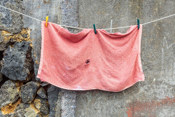  An old red towel hangs on the background of an old cement wall at Sao Miguel island, Portugal