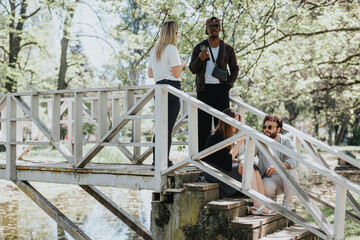 Casual meeting of young adults on a wooden bridge in a city park, expressing carefree lifestyle...
