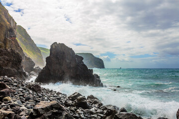 Atlantic ocean wave breaks on the big rocky stone on the beautiful beach of Sao Miguel island
