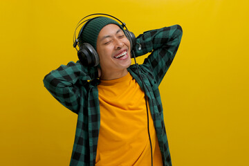 Asian man in a beanie and casual clothes stretches his muscles after work, listening to music on...