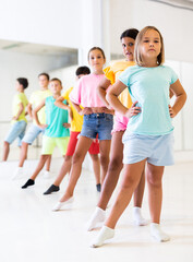Obraz premium Smiling children primary school age rehearsing movements of ballet dance in modern studio