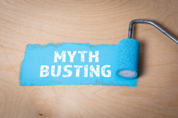 MYTH BUSTING. Blue paint and paint roller on a plywood background