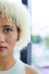 Biracial young woman, curly blonde hair, nose ring, subtle makeup, calm in office