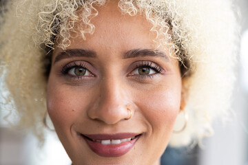 In modern office, biracial young female with curly blonde hair, smiling