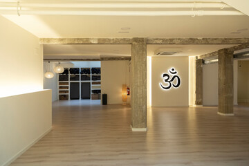 Serene yoga space with ambient lighting and iconic Om symbol illuminated on the wall.