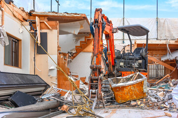 An orange backhoe loader equipped with a hydraulic excavator attachment to be able to grab heavy...