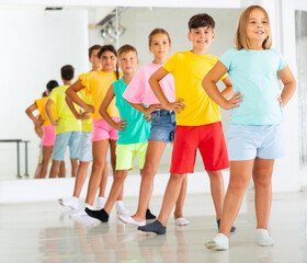 Group of positive children rehearsing movements of ballet in classroom