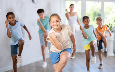 Positive female child dances vogue in choreographic school. Group of young people in sportswear...