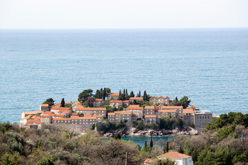 Sveti Stefan Island in the Adriatic Sea, Montenegro. Island with houses and trees. See through the trees from above. Balkans. Background