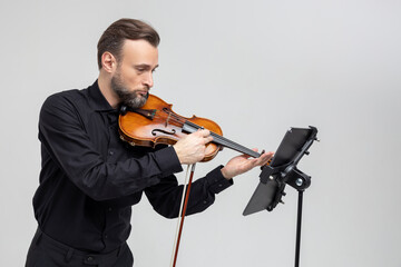 Handsome man holding a violin in his hands playing classic music