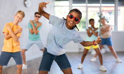 Positive boy exercising in group of classmates during dance class at school