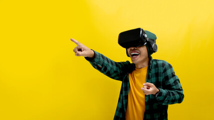 Young Asian man wearing a VR headset points his finger forward, interacting with a virtual reality...