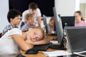 Tired girl student sleeps while sitting at computer in classroo