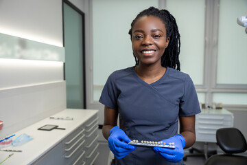 Smiling young female dentist in the office ready for dental prosthetics