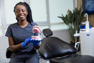 Smiling young female dentist in the office ready for dental prosthetics