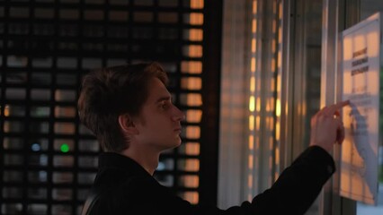 Side view of young student reading notice at university entrance