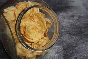 close up view of Emping, Indonesian traditional snack made from melinjo or belinjo seeds. Bitter and savory. served on transparent food container with black background