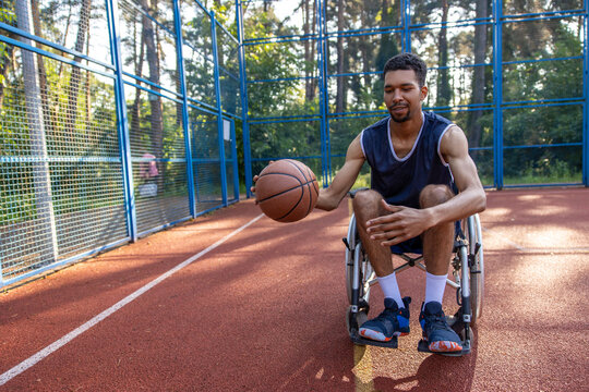 Basketball player in wheelchair playing basketball on open air ground