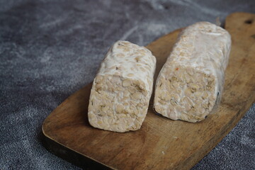 Raw tempeh or tempe mentah, is a typical Indonesian food made from fermented soybeans. Raw tempeh on wooden cutting board