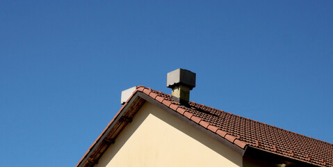 Chimney pots on a red tiled roof of a country house and gutter on the sides