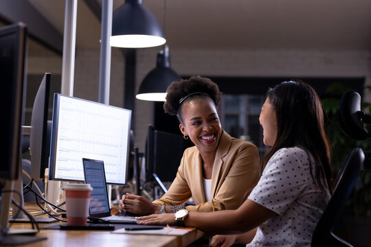 At office, diverse female business colleagues discussing work and working late