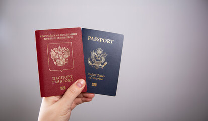 A female hand holding an American passport and a Russian passport