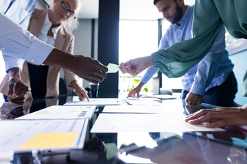 A diverse team at office, exchanging business papers on table